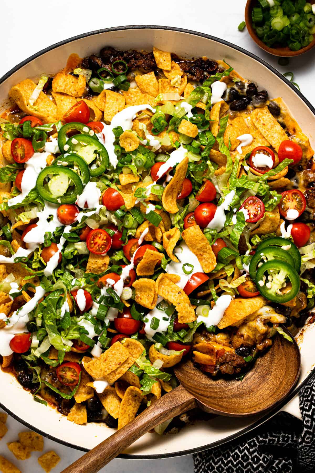Overhead shot of a large pan filled with walking taco casserole garnished with sour cream