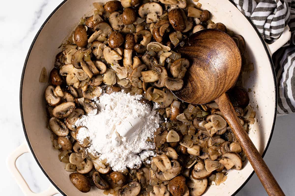 Large white pan filled with sautéed mushrooms and flour