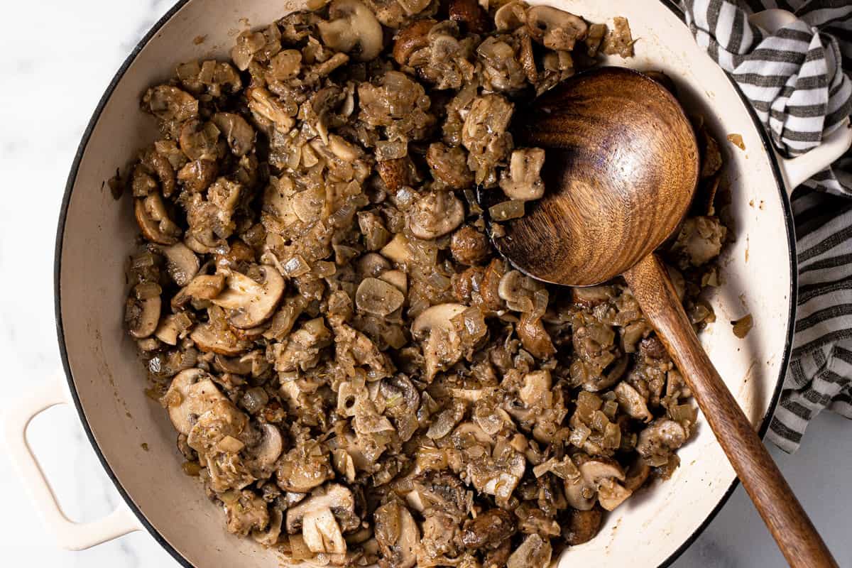 Large white pan filled with sautéed mushrooms coated in flour
