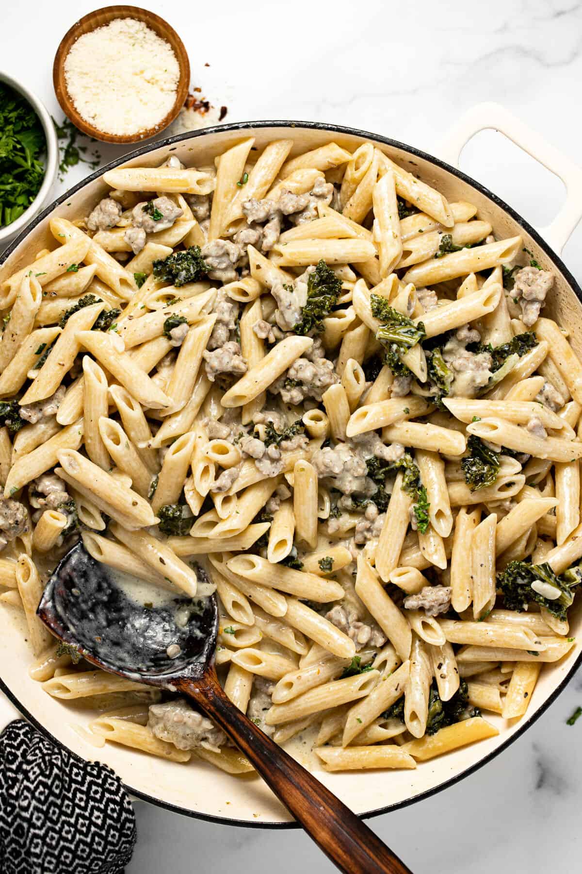 Large white pan filled with Italian sausage and kale pasta