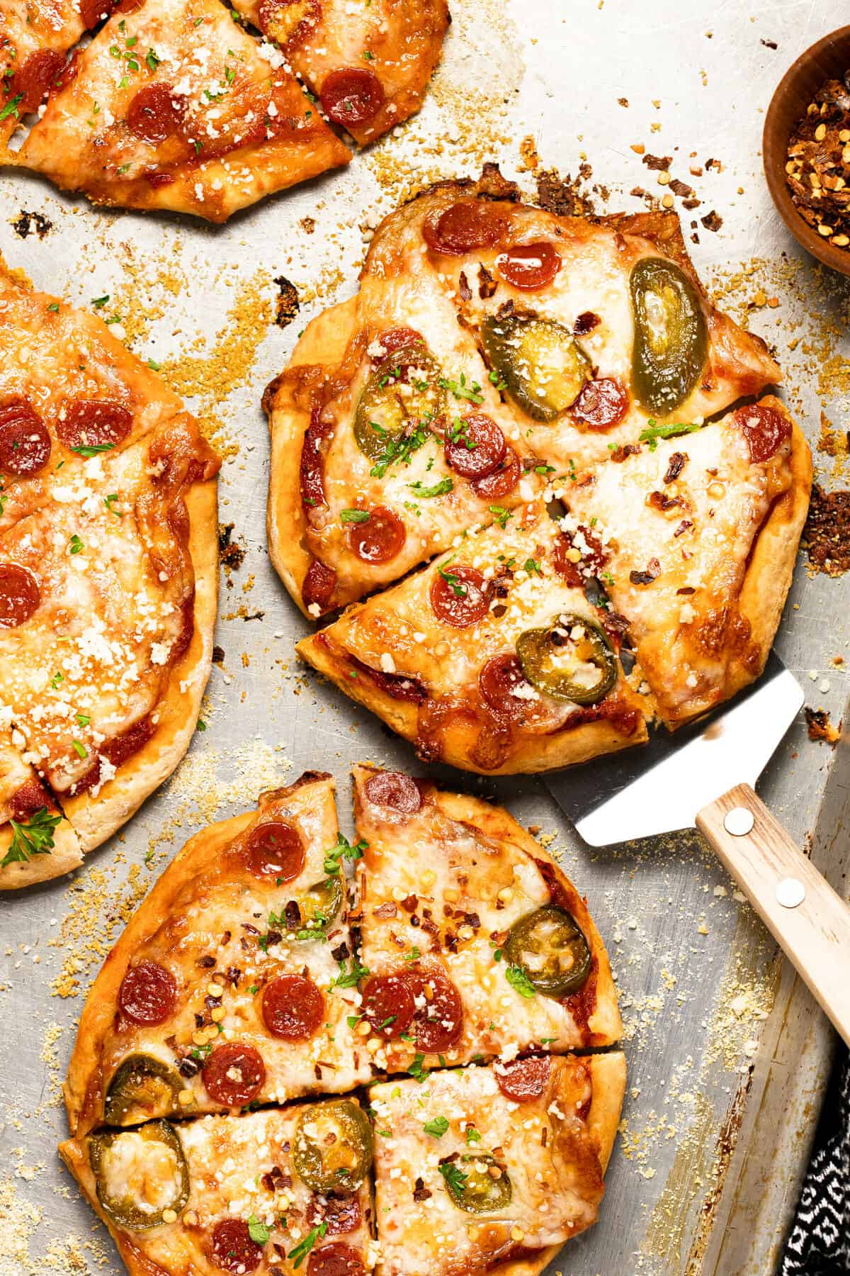 Baking sheet with homemade mini pizzas garnished with grated Parmesan cheese