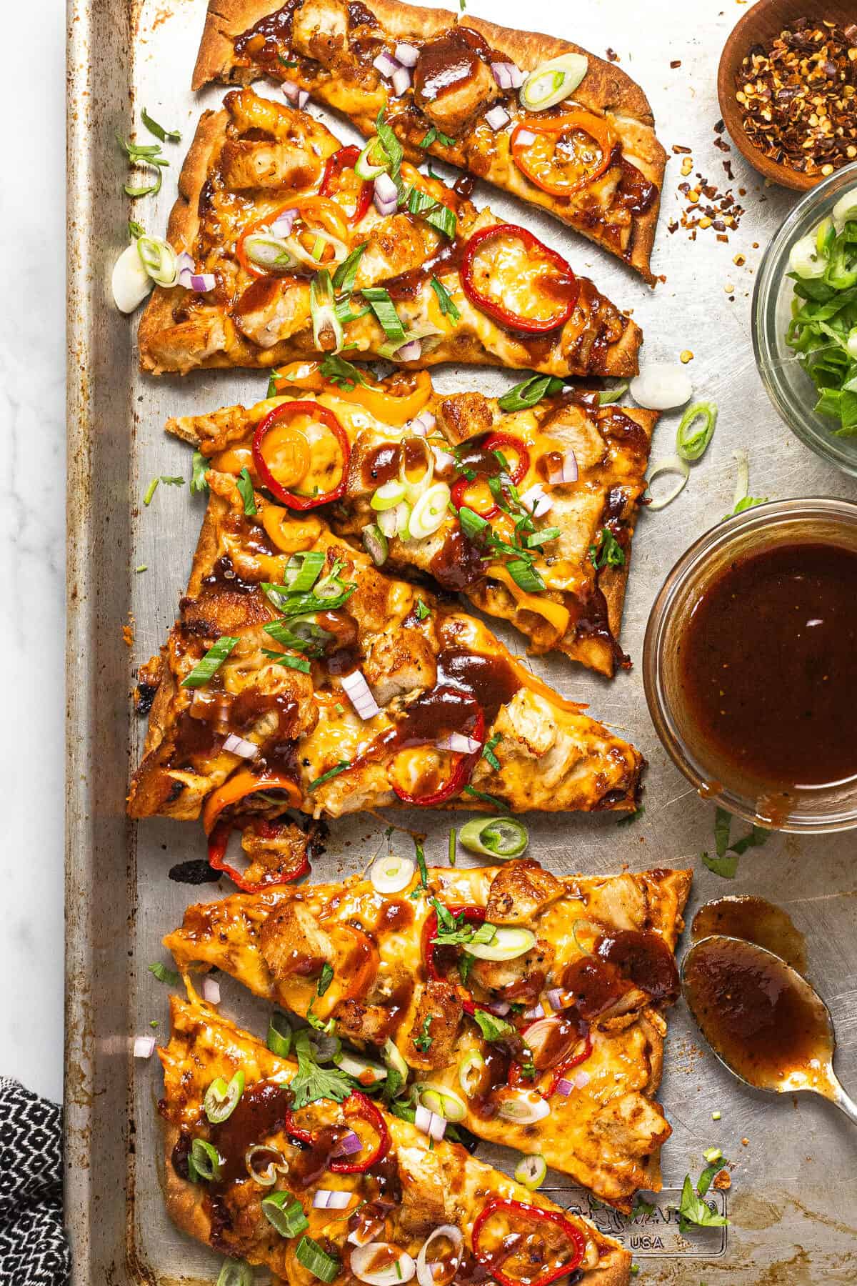 Baking sheet with a BBQ chicken flatbread garnished with sliced green onion