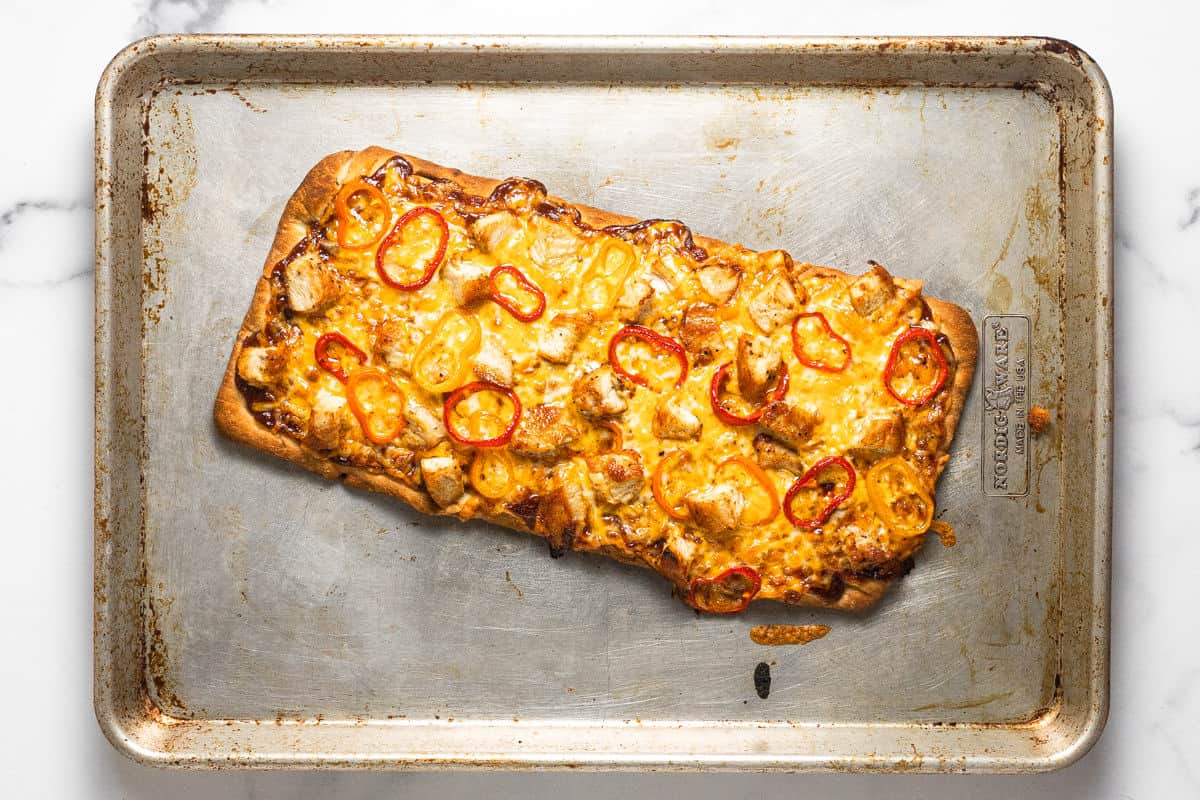 Freshly baked BBQ chicken flatbread on a large baking sheet