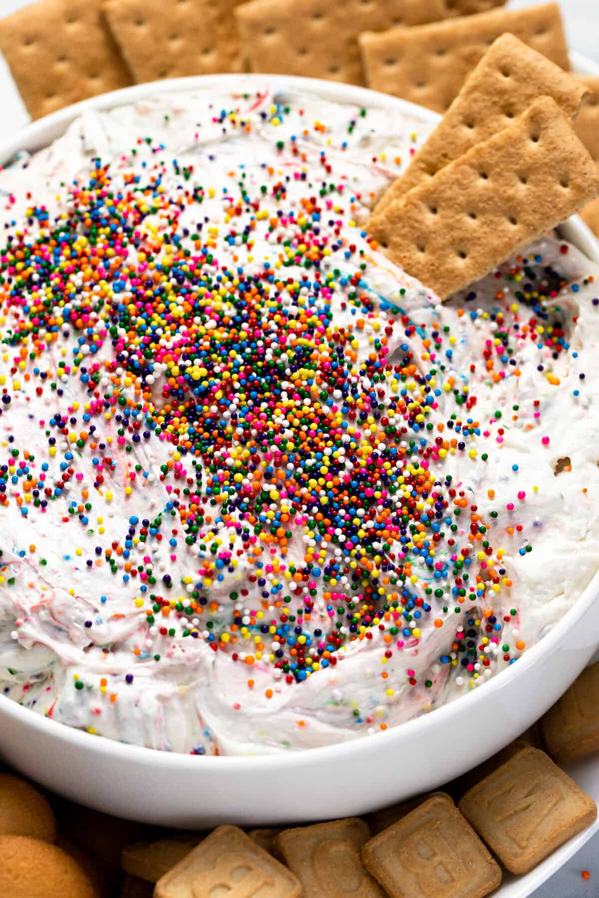White serving bowl with creamy Dunkaroo dip with graham crackers dipped in it