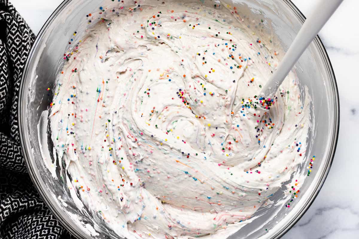 Glass bowl filled with ingredients to make funfetti dip