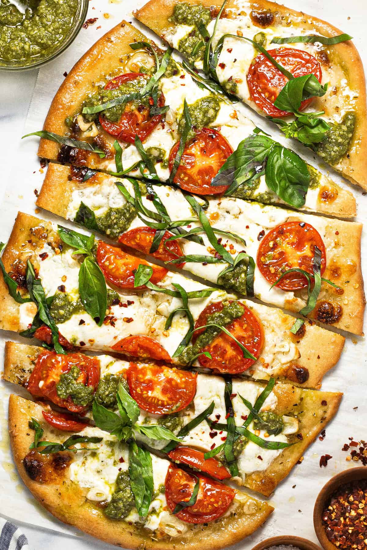 Close up shot of sliced margherita flatbread pizza garnished with basil