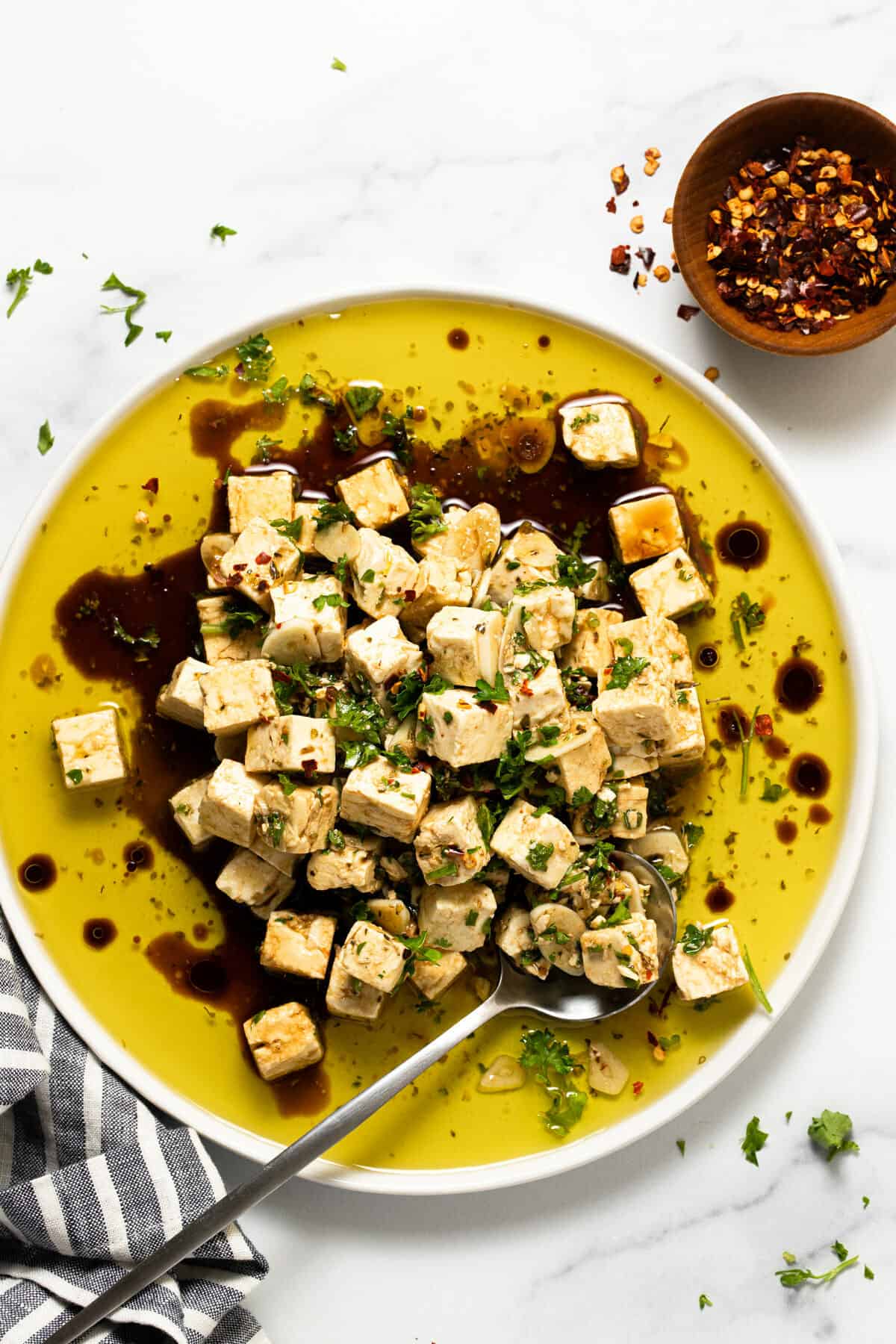 White plate filled with marinated squares of feta garnished with parsley