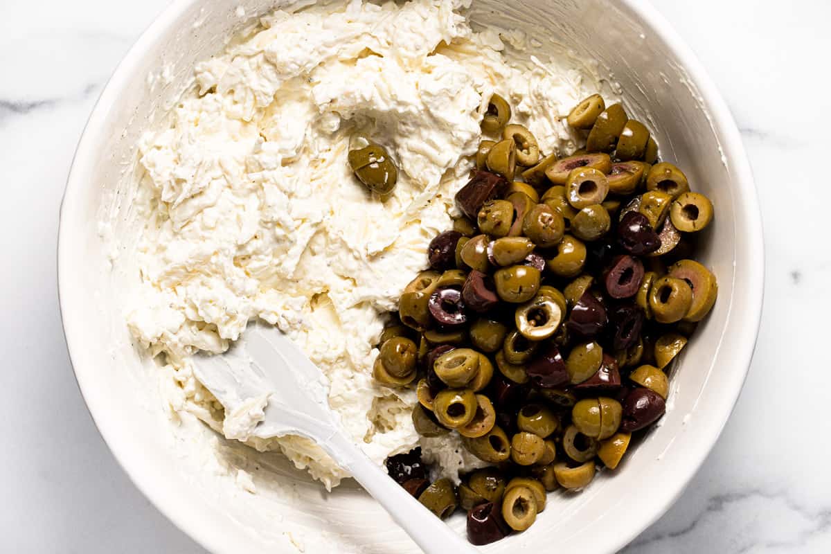White bowl filled with ingredients to make baked olive dip