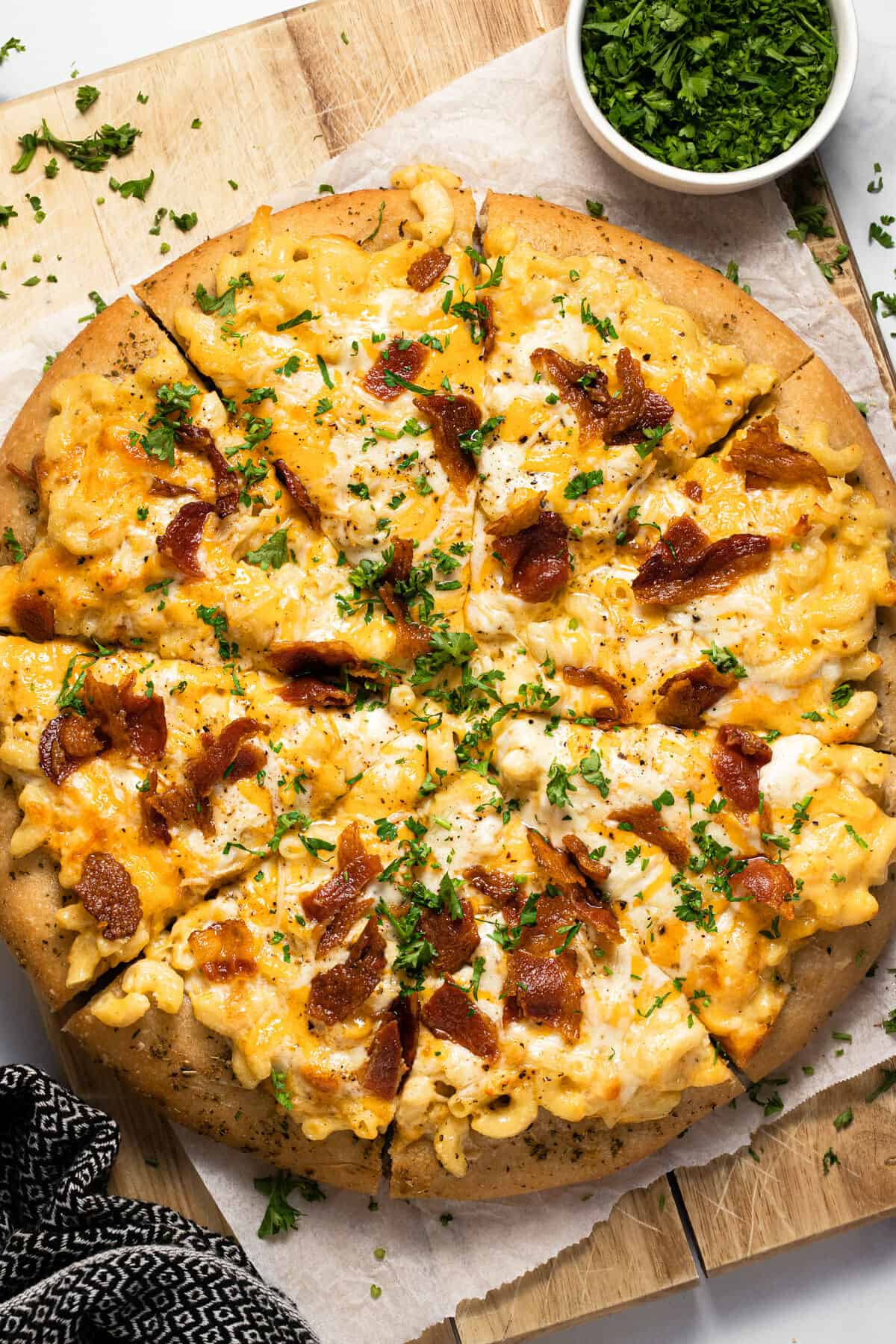Homemade mac and cheese pizza on a wooden cutting board