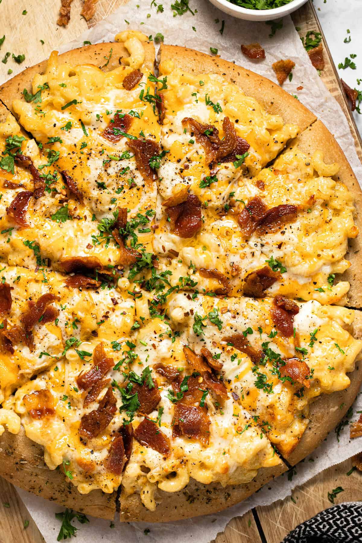 Homemade mac and cheese pizza on a wooden cutting board