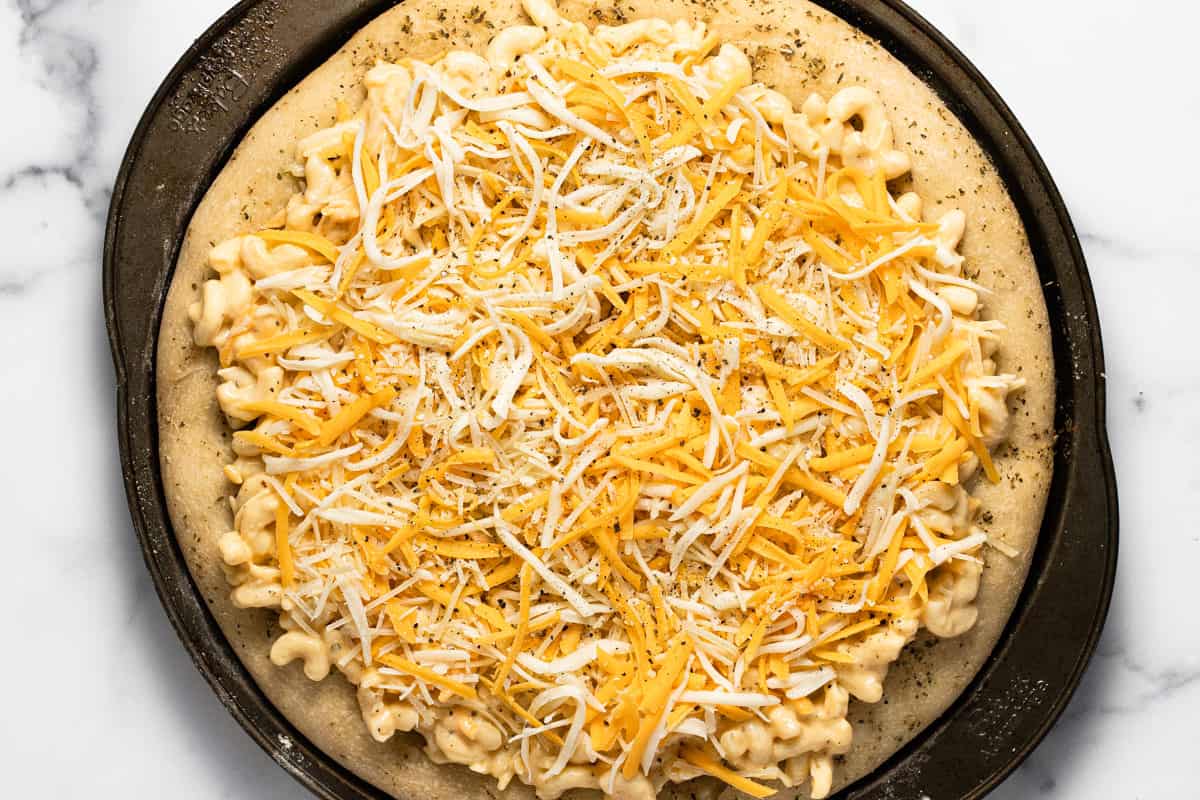 Mac and cheese pizza on a pizza pan just before baking it