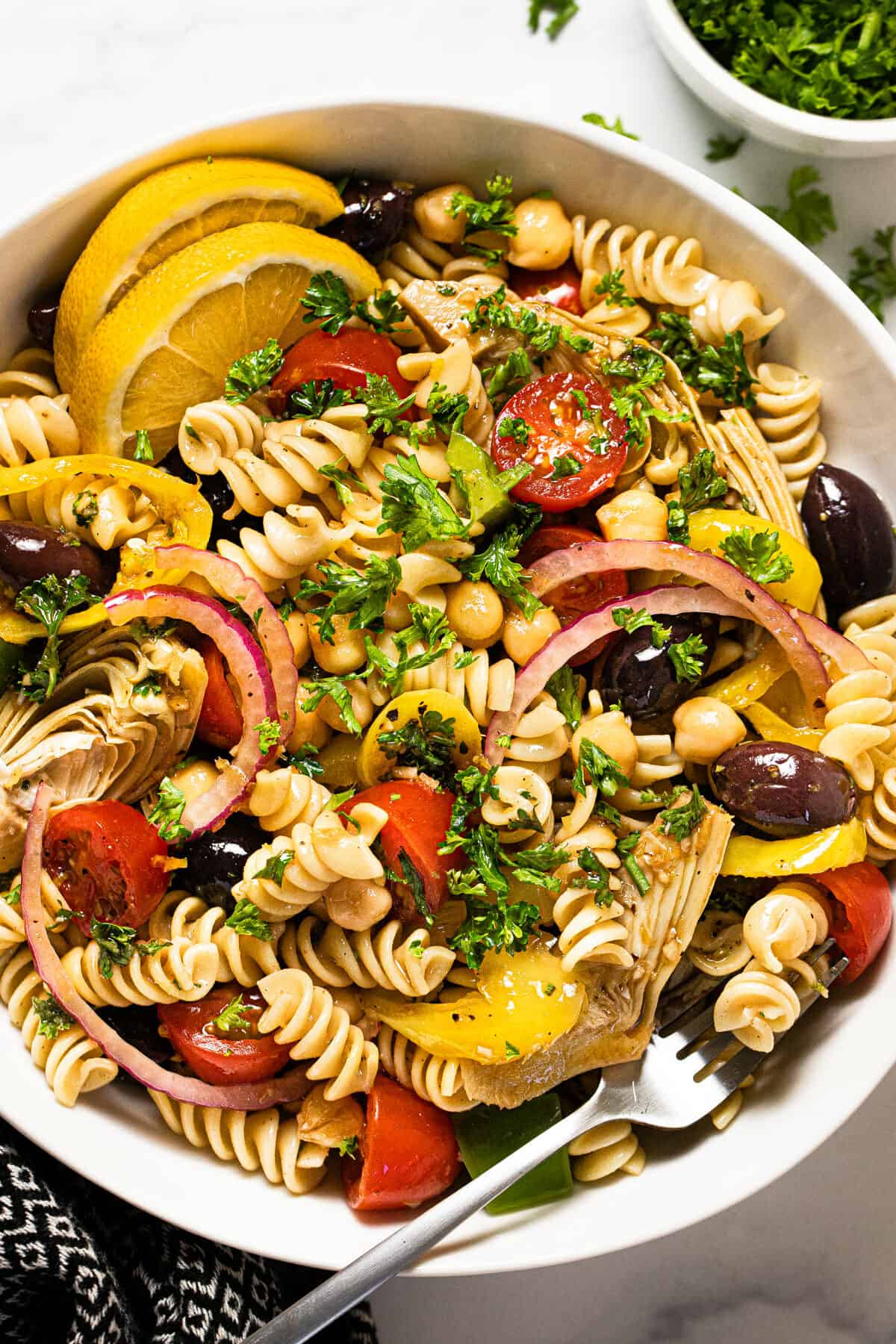 Overhead shot of a bowl of vegan pasta salad garnished with chopped parsley