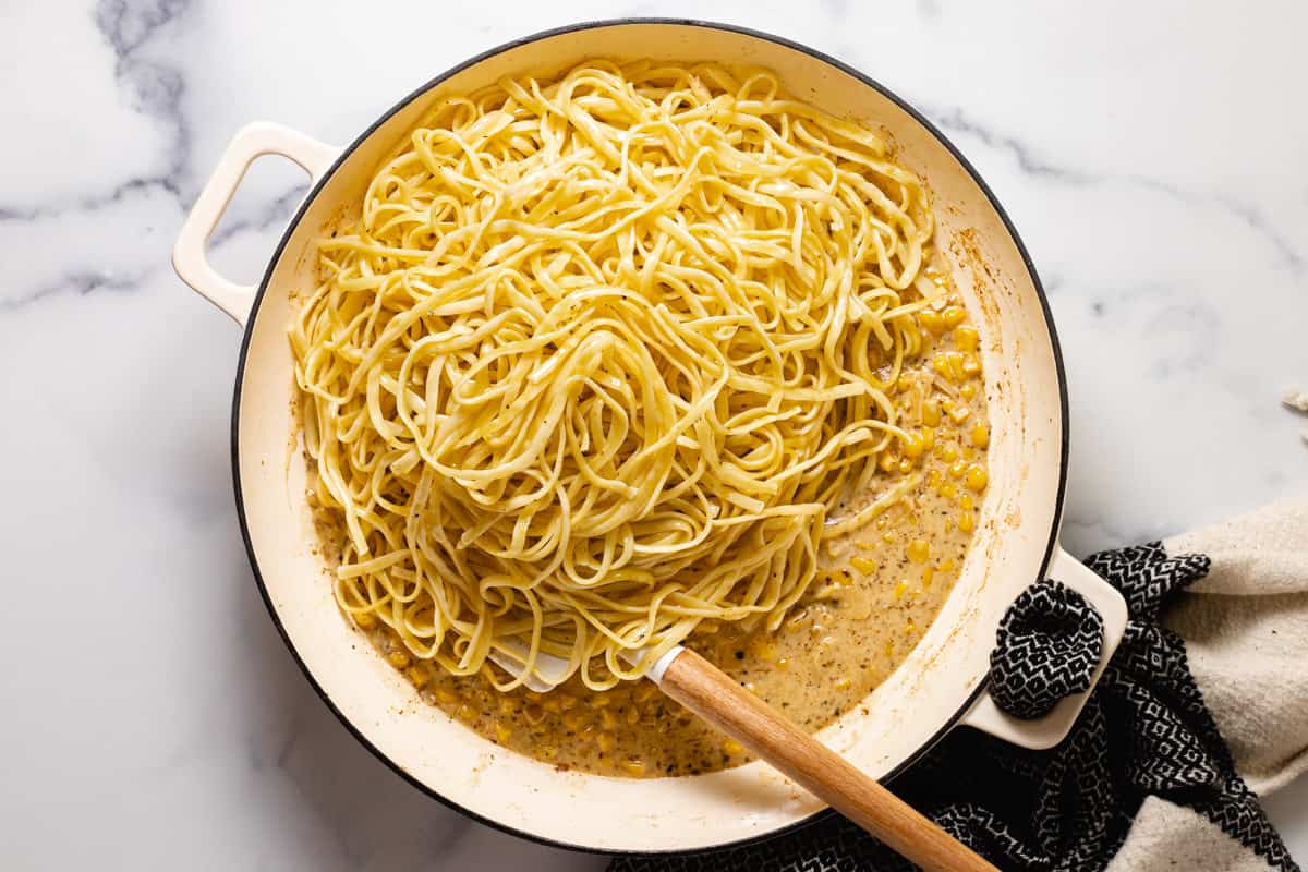 Large sauté pan filled with creamy corn sauce and cooked linguine