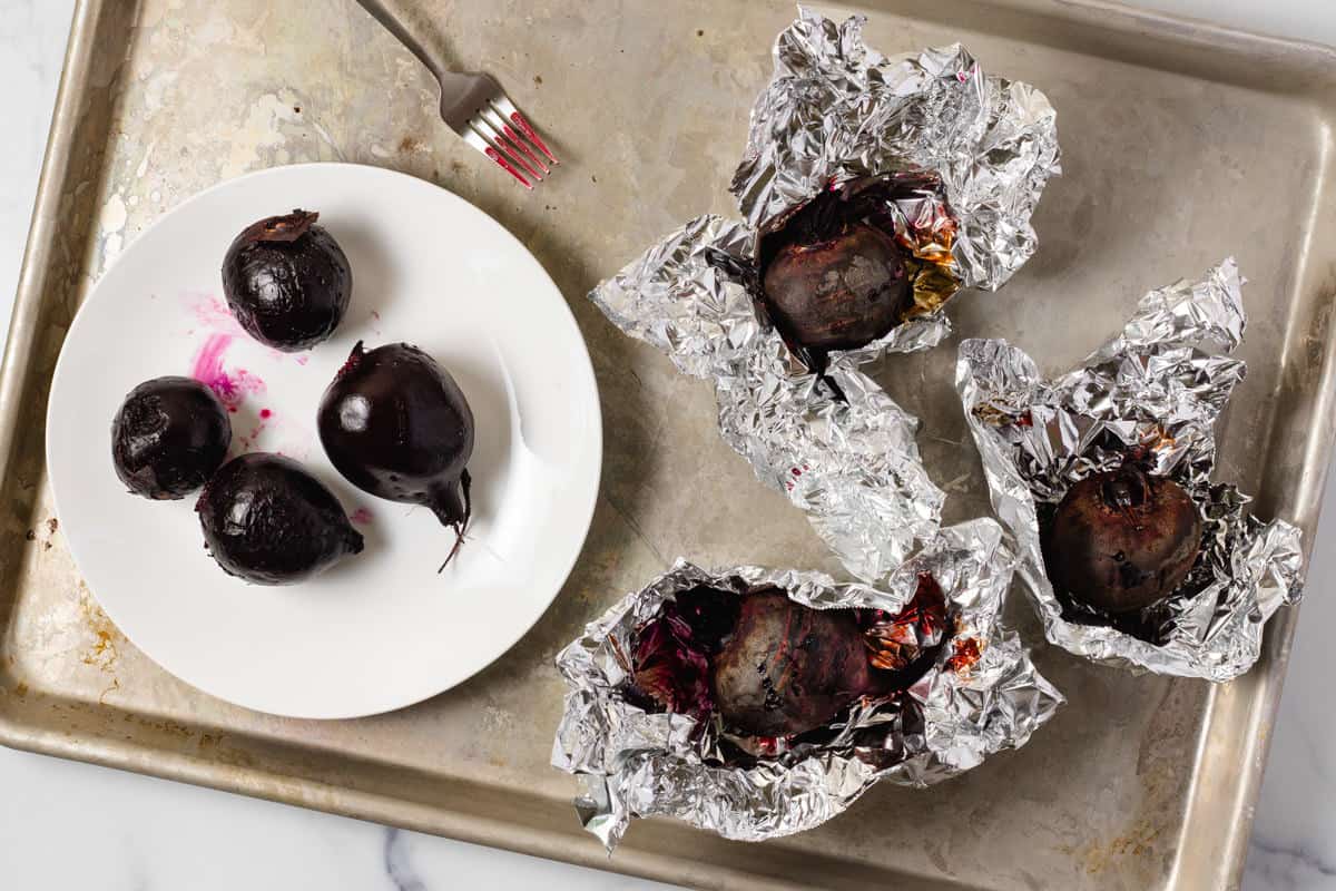 Metal baking sheet with roasted beets wrapped in foil