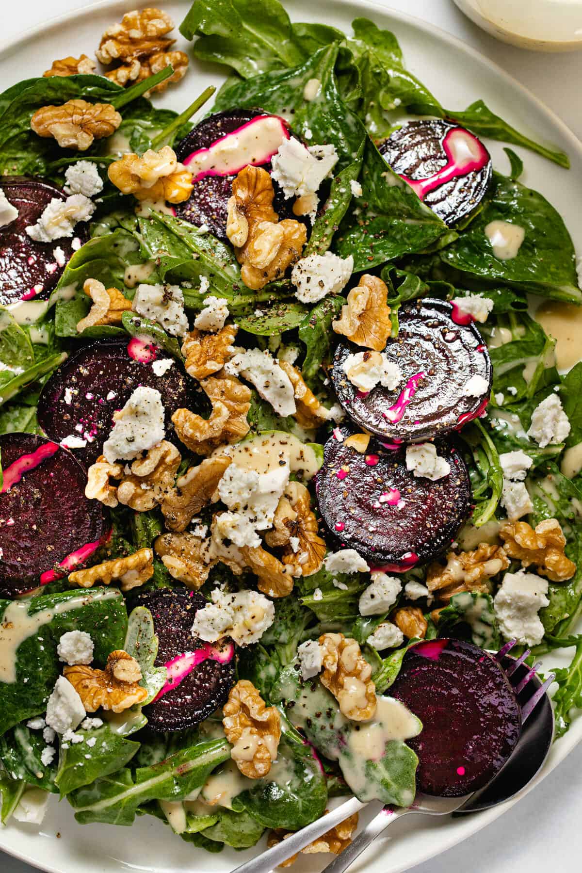 Overhead shot of a white plate filled with beet salad with feta and walnuts