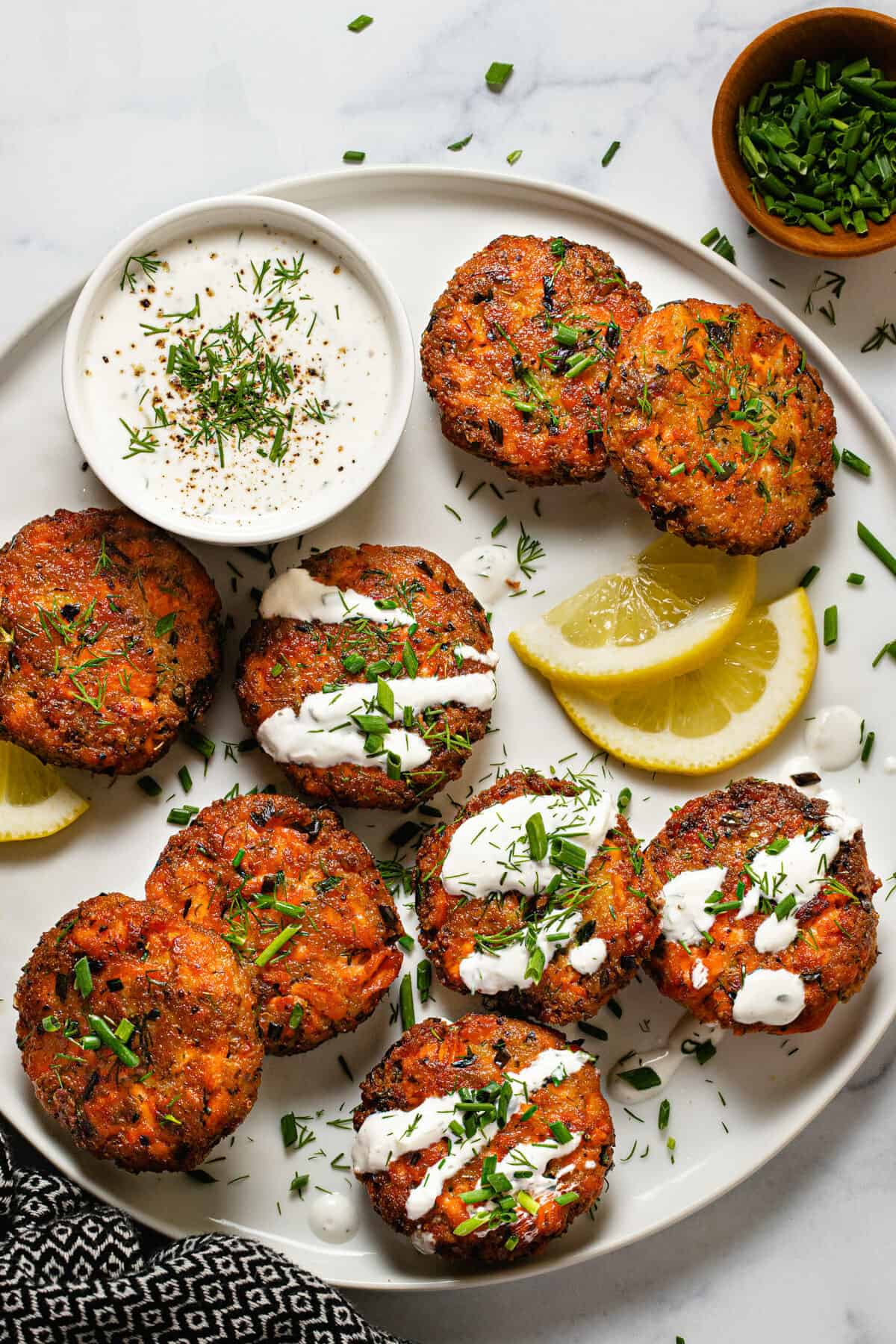 White plate filled with homemade salmon cakes garnished with fresh dill