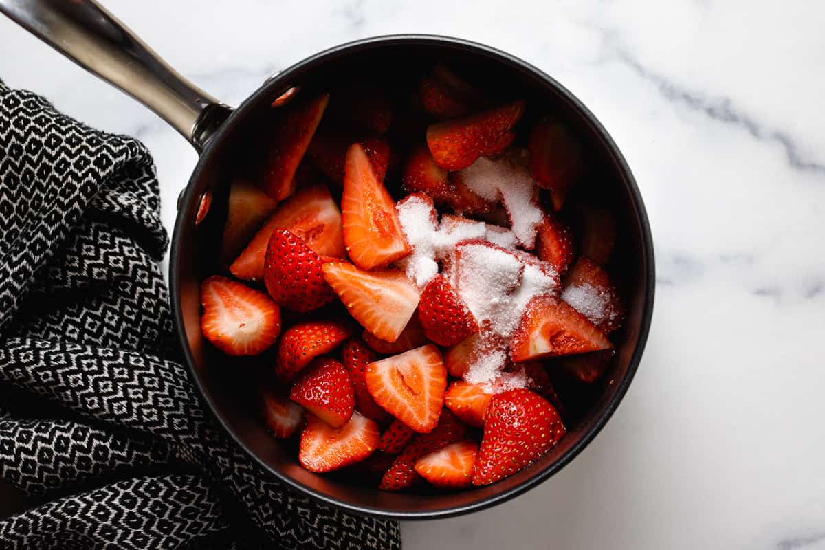 Medium saucepan filled with ingredients to make strawberry compote