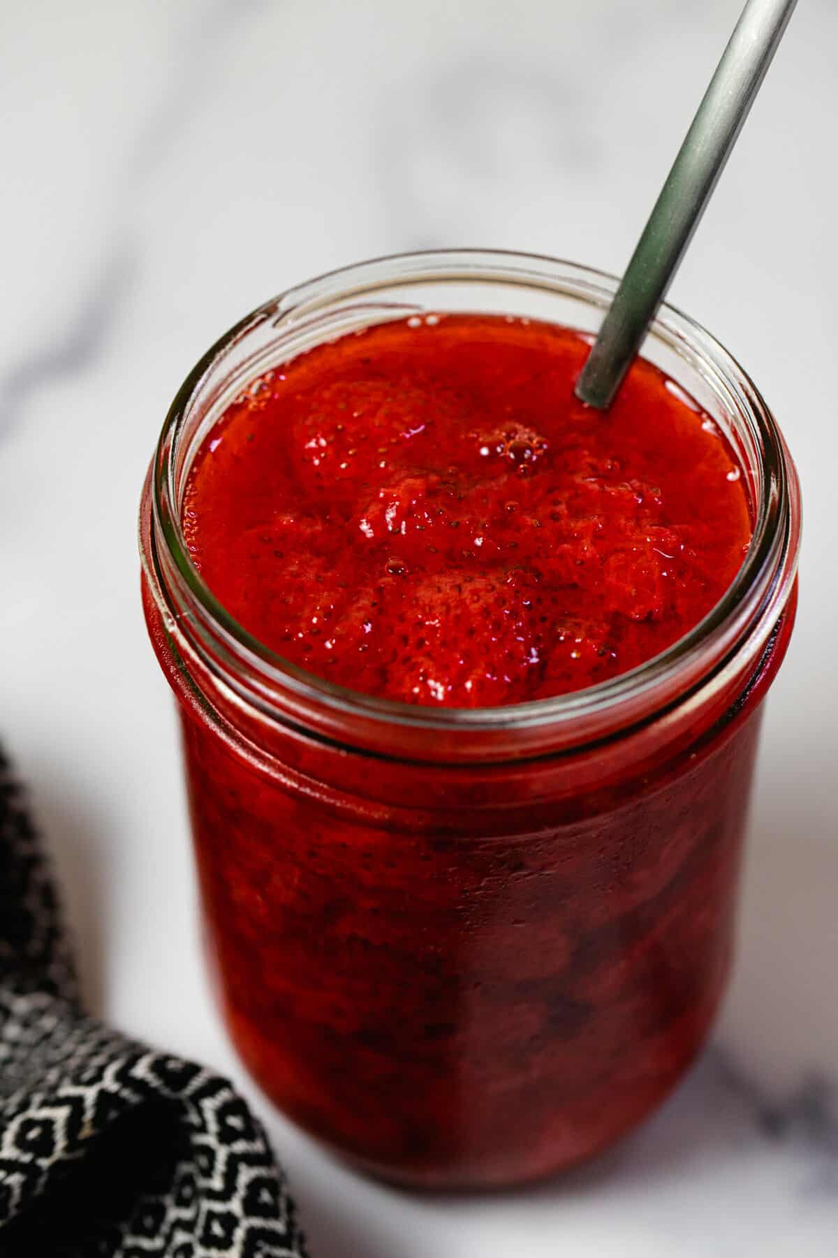 Wide mouth mason jar filled with homemade strawberry sauce