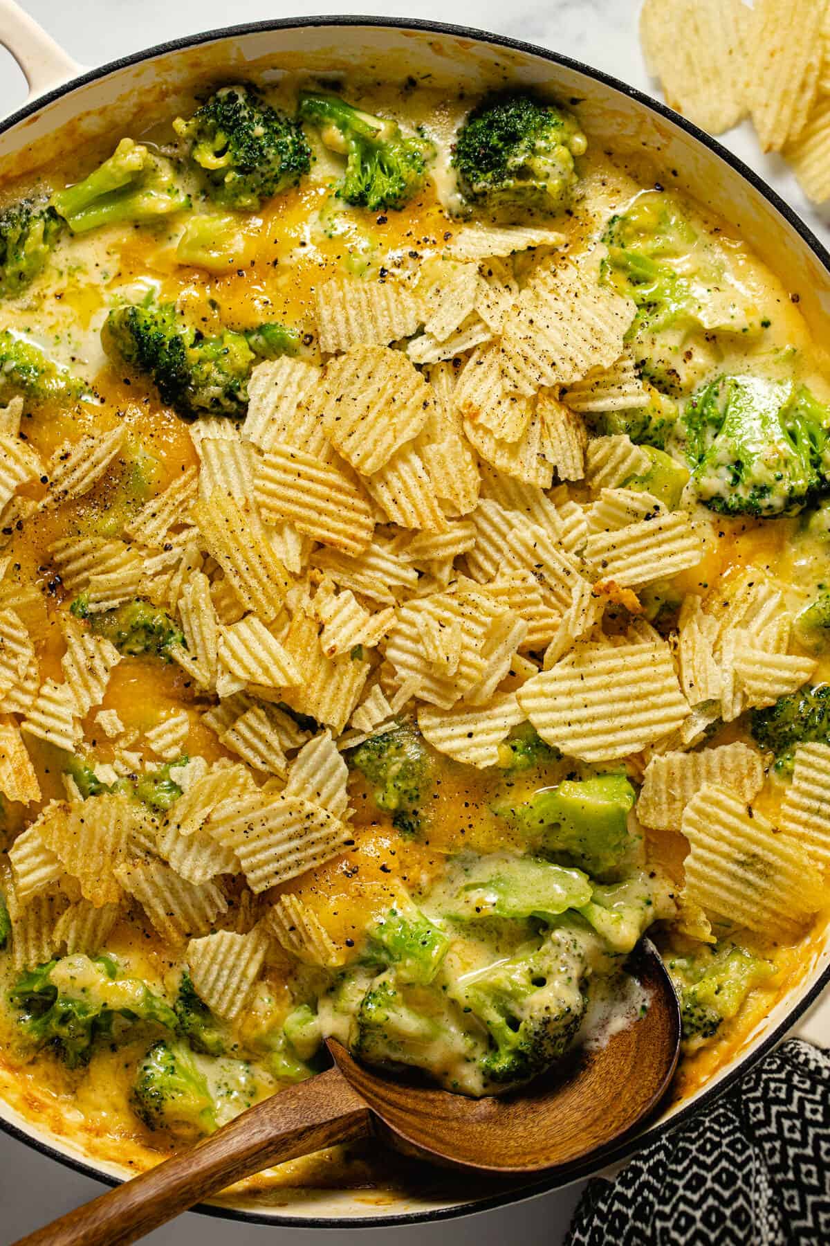 Overhead shot of a large white pan filled with broccoli cheese casserole topped with potato chips