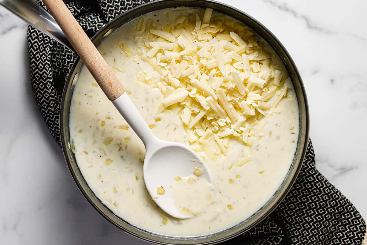 Large pan filled with cream sauce and shredded cheese
