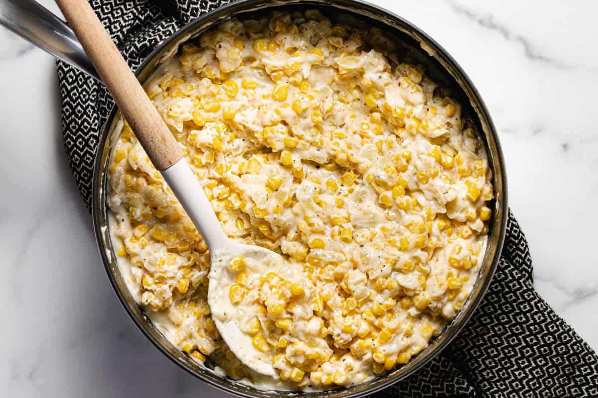 Large pan filled with frozen corn in a creamy cheese sauce