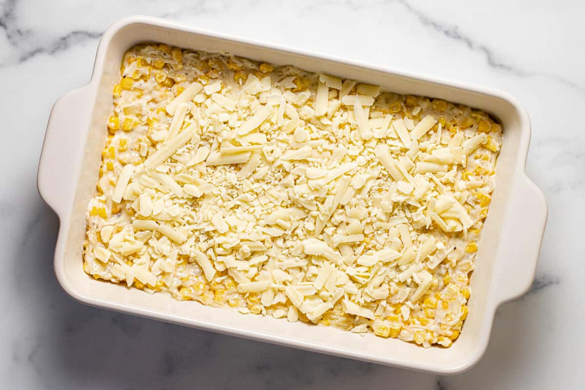 White baking dish creamy corn bake topped with shredded cheese