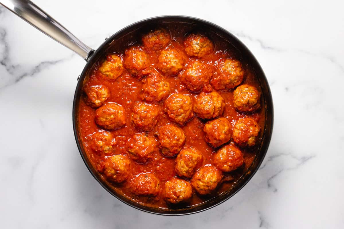 Meatballs in a large pan filled with spaghetti sauce