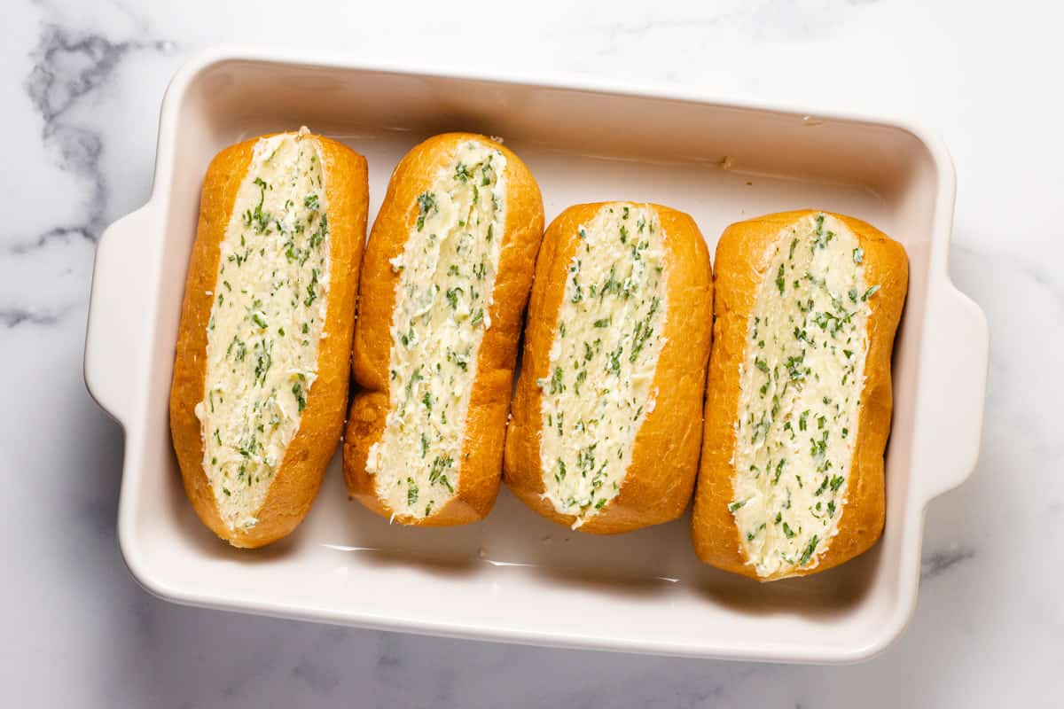 Garlic buttered hoagie rolls in a large baking dish