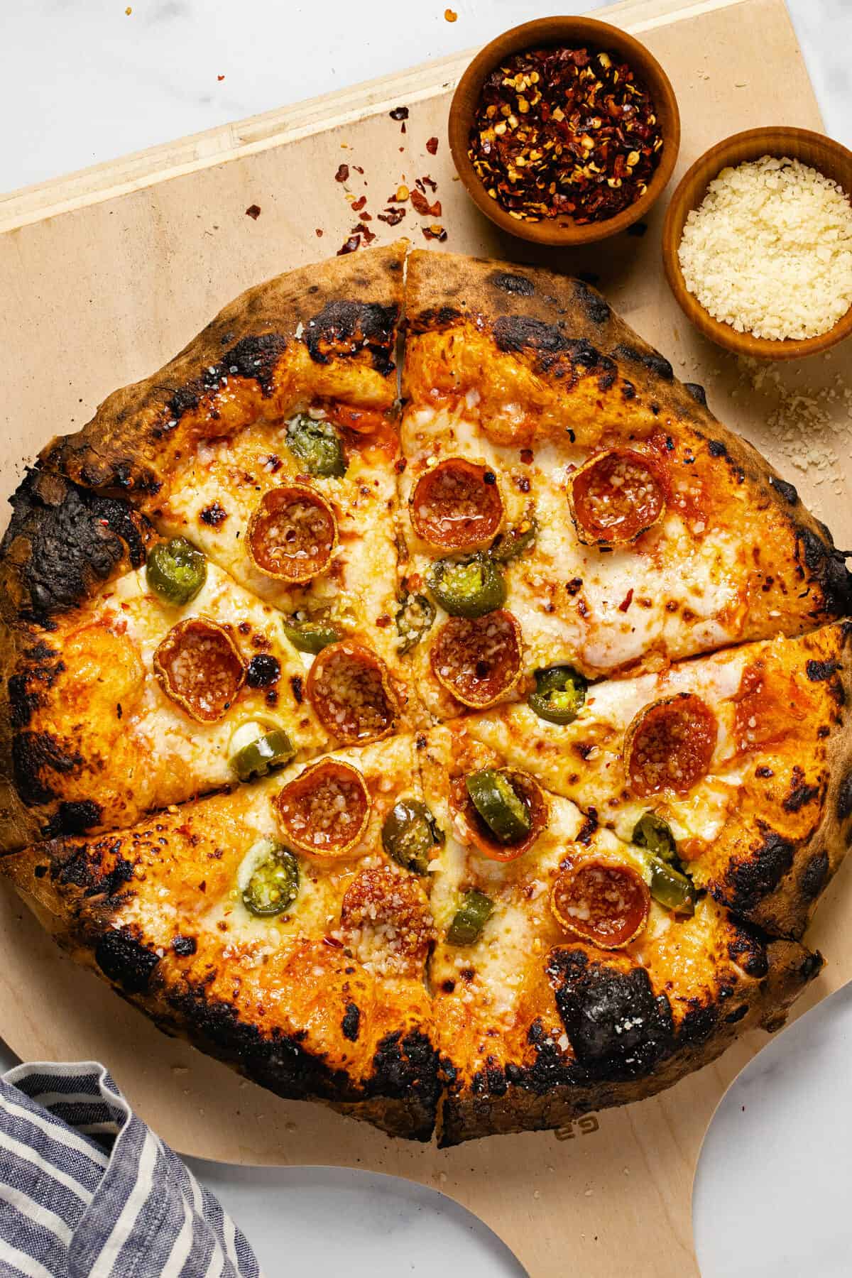 Overhead shot of a pepperoni jalapeno pizza on a wooden pizza peel