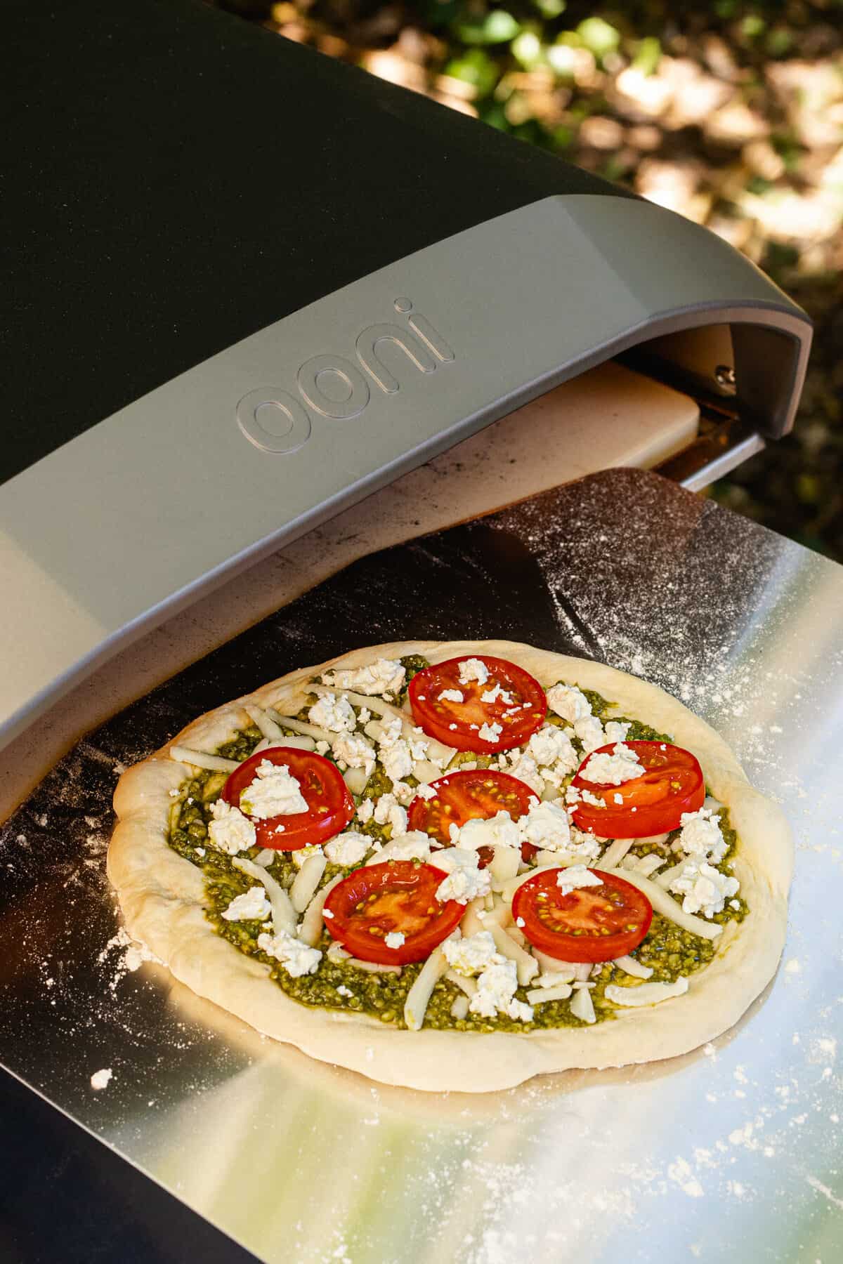 Goat cheese and tomato pizza going into an Ooni pizza oven
