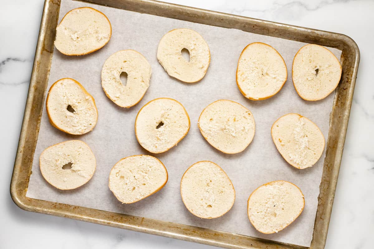 Plain mini bagels on a parchment lined baking sheet