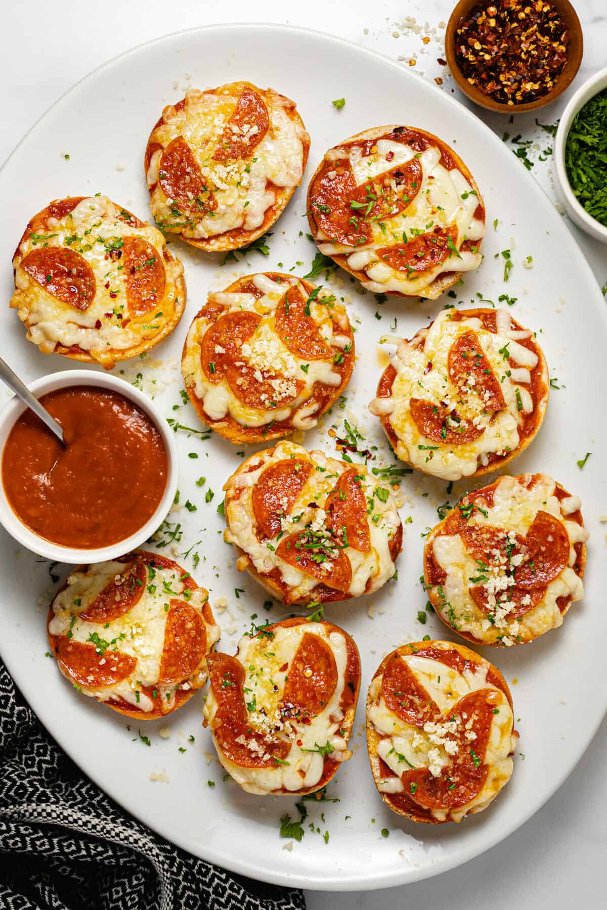 Large white platter filled with homemade pizza bagel bites garnished with parsley