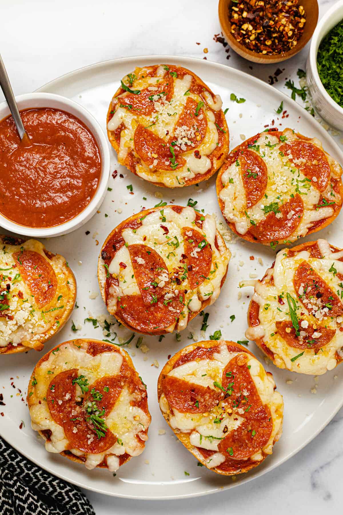 White plate filled with homemade pizza bagel bites garnished with parsley