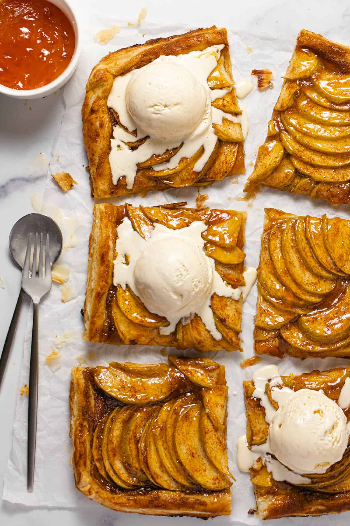 Overhead shot of a sliced puff pastry apple tart topped with ice cream
