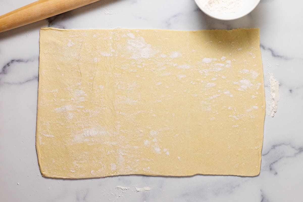Puff pastry crust rolled out on a marble counter top