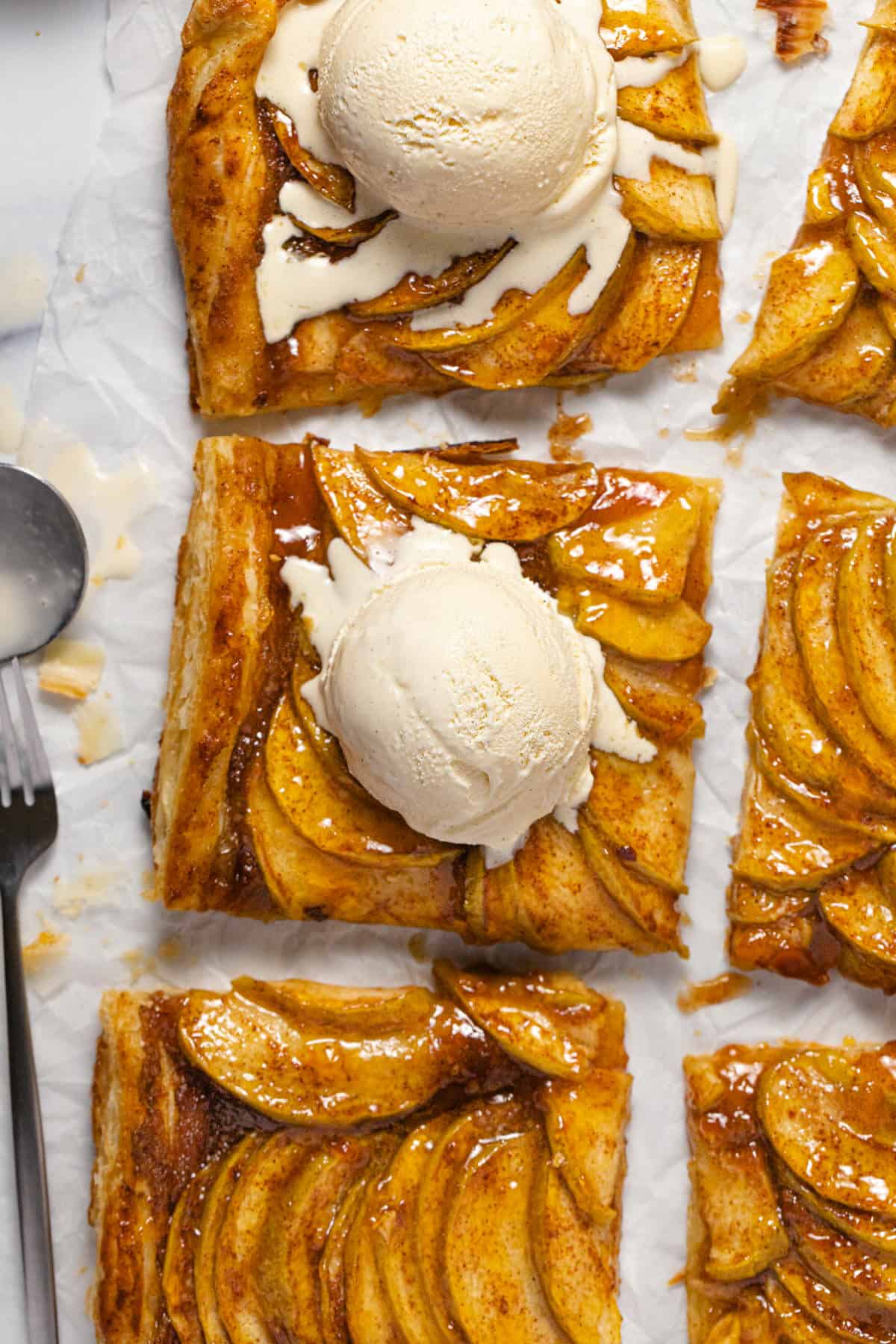 Overhead shot of a sliced puff pastry apple tart topped with ice cream