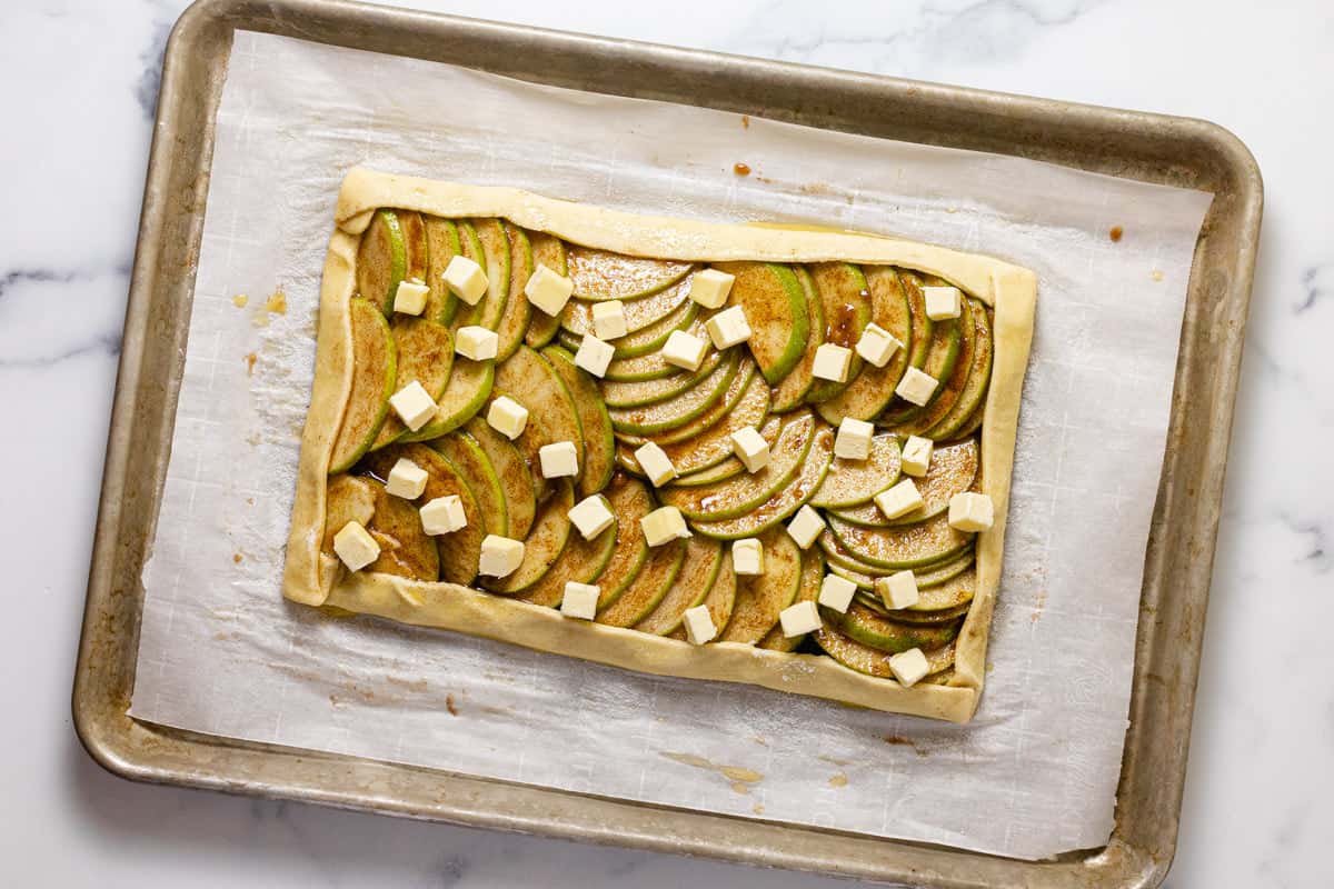 Homemade puff pastry apple tart on a parchment lined baking sheet ready to go in the oven