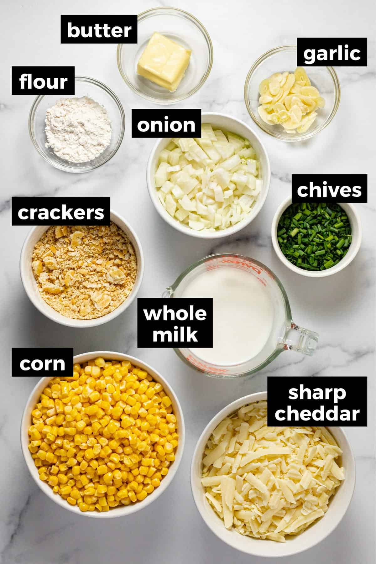 White marble counter top with ingredients to make cheesy corn casserole