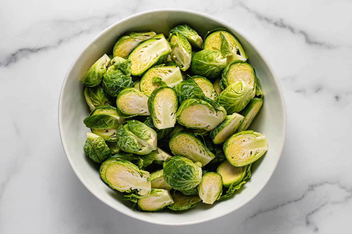 White bowl filled with halved Brussel sprouts