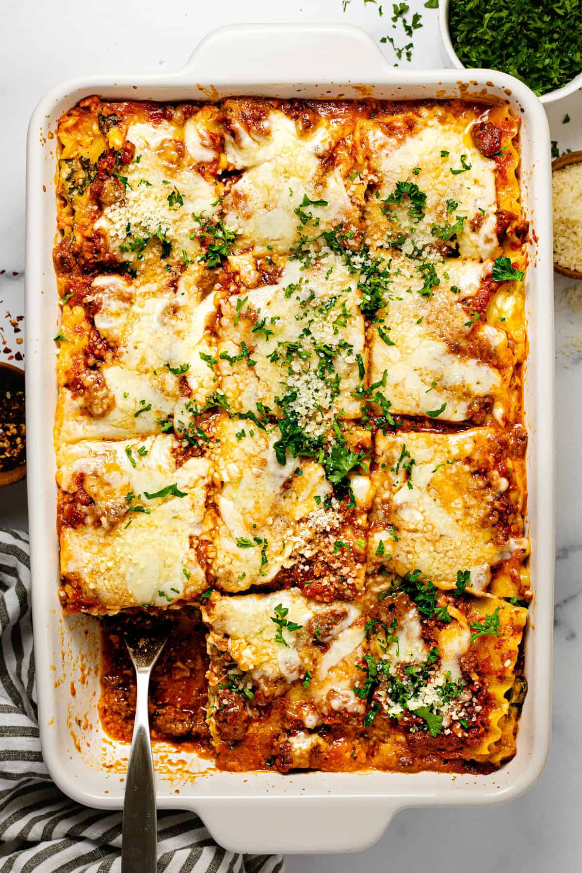 Large white baking dish filled with homemade cottage cheese lasagna garnished with parsley 