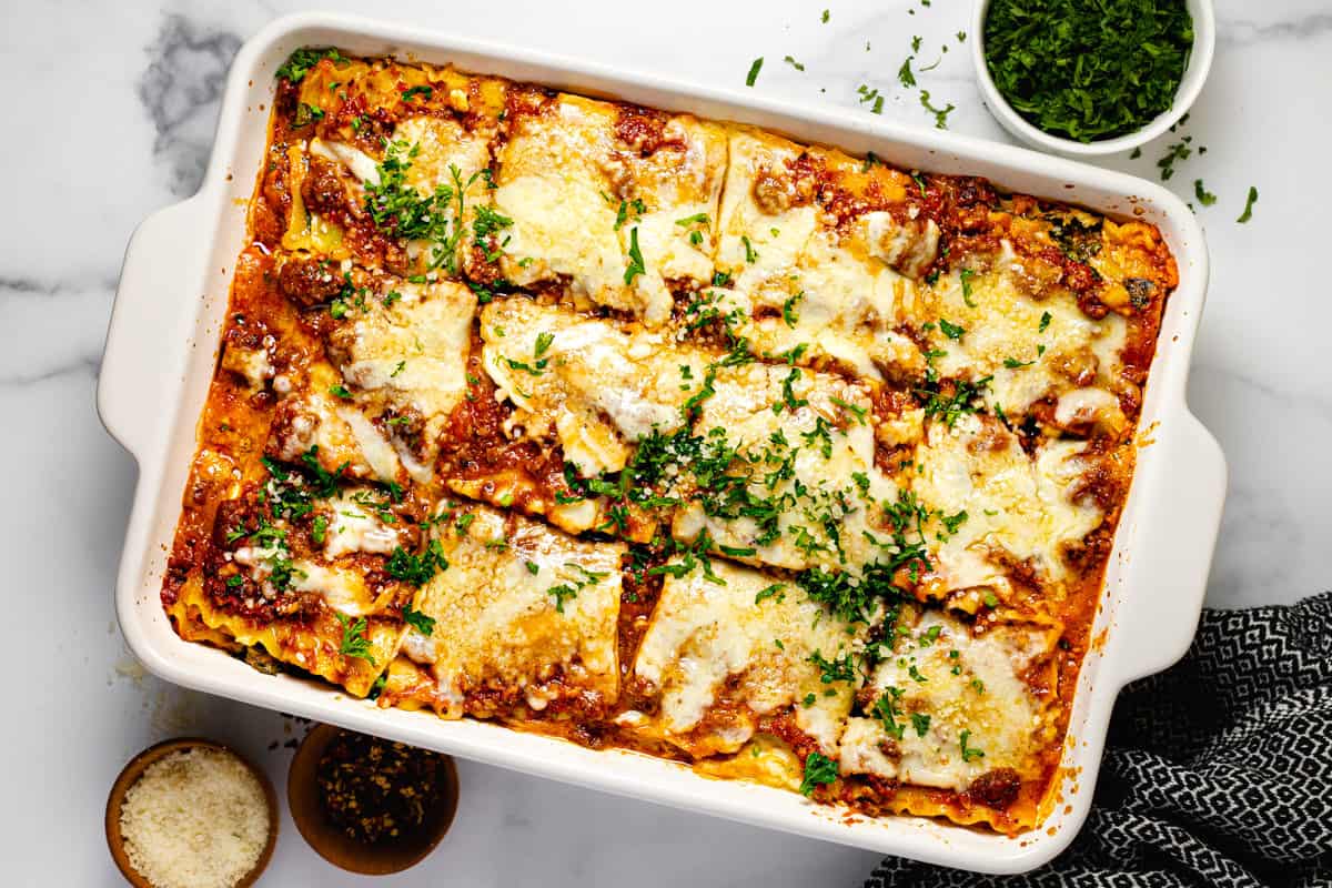 Large white baking dish filled with homemade cottage cheese lasagna garnished with parsley 