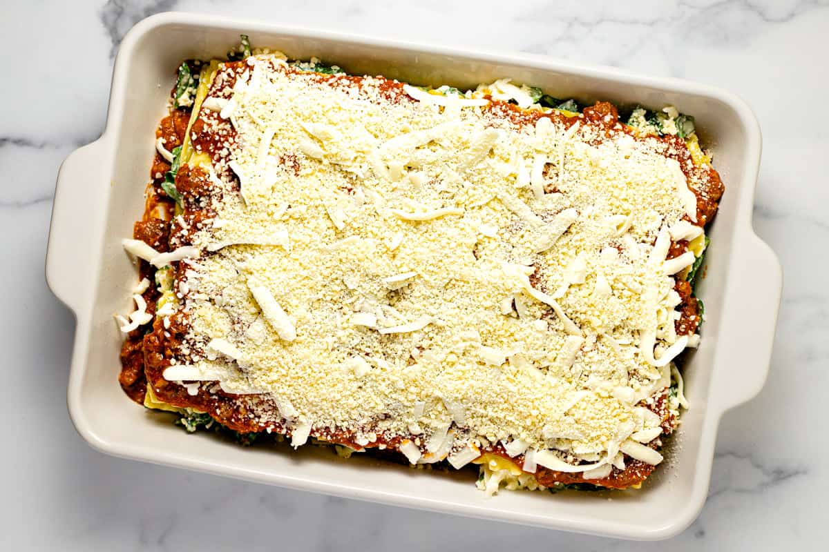 White baking dish filled with ingredients to make meaty cottage cheese lasagna