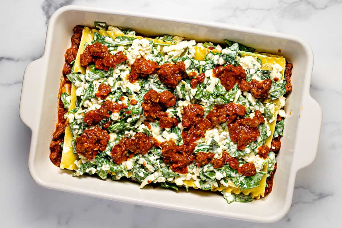 White baking dish filled with ingredients to make meaty cottage cheese lasagna