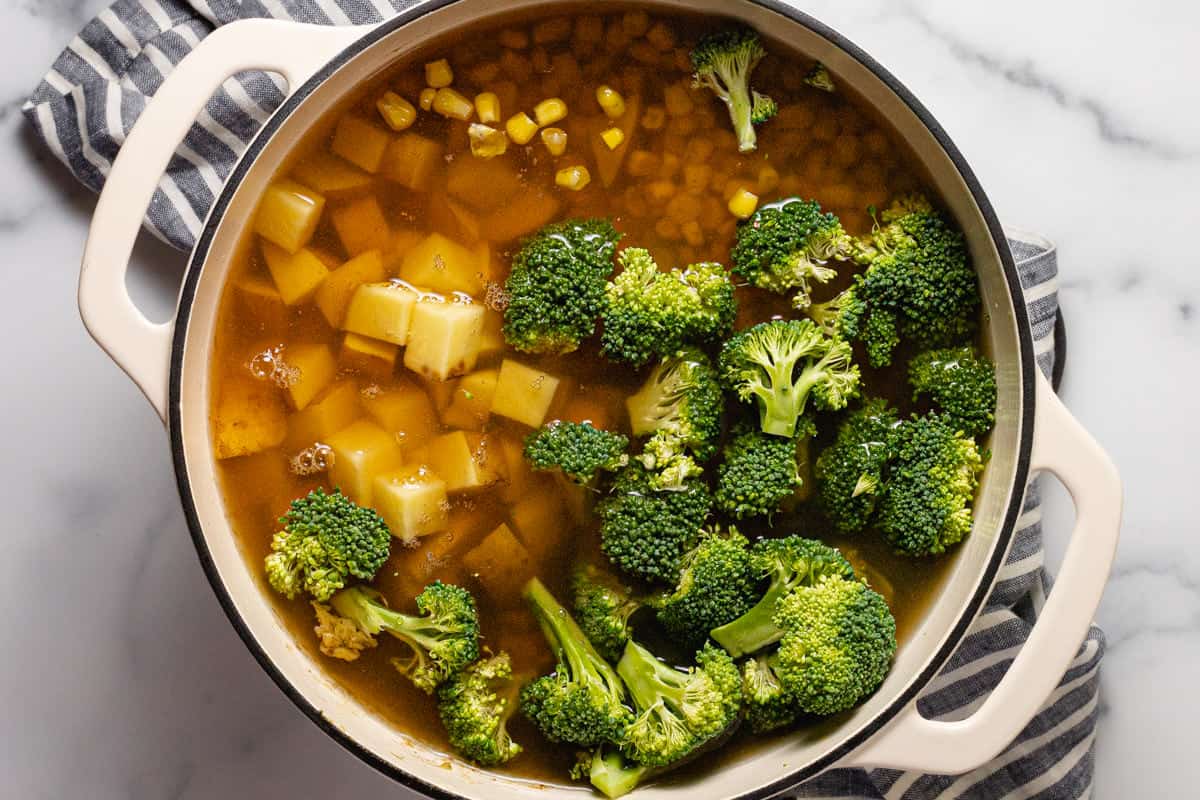 Large white pot filled with ingredients to make creamy vegetarian soup