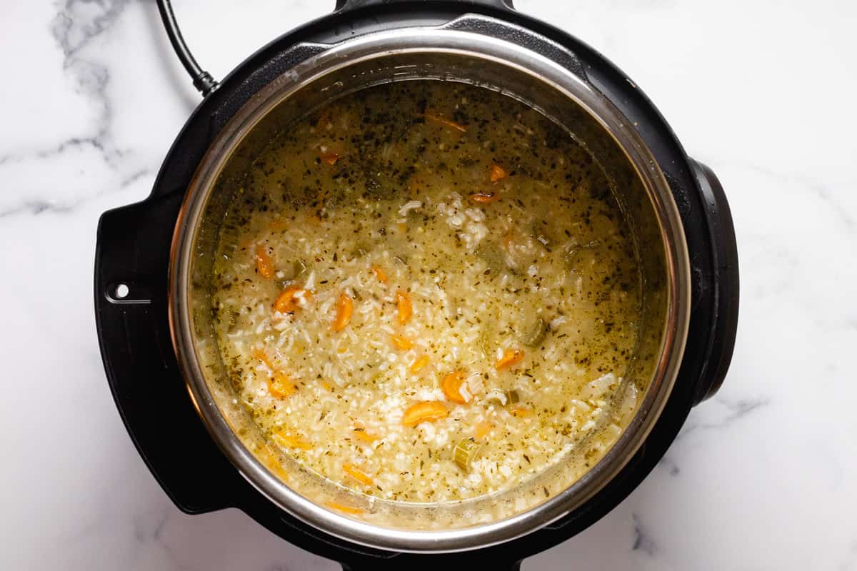 Instant pot filled with ingredients to make chicken and rice soup