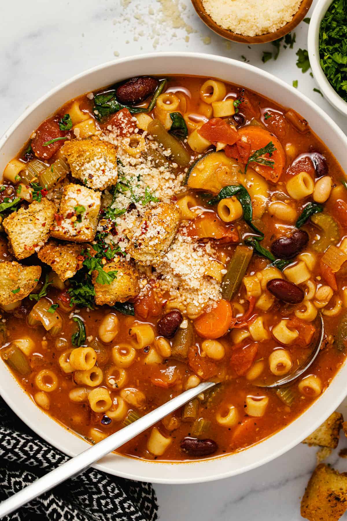 Overhead shot of a white bowl filled with vegetarian minestrone soup garnished with parsley