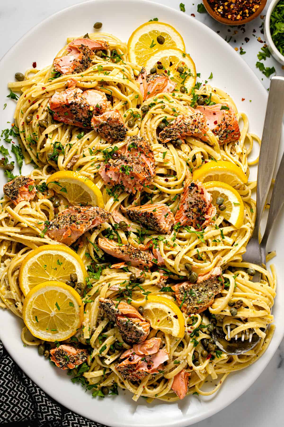 White platter filled with salmon linguine in a garlic herb sauce garnished with parsley.