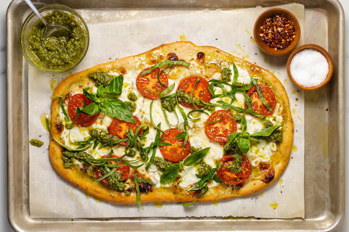 Margherita flatbread pizza on a parchment lined baking sheet