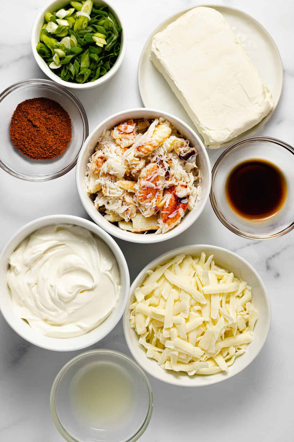 White marble counter top with bowls of ingredients to make creamy baked crab dip