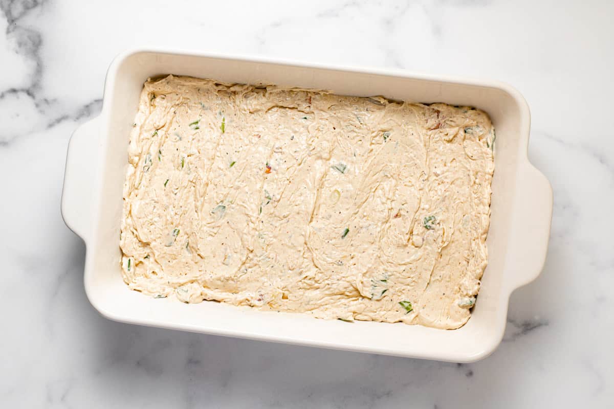 Creamy crab dip spread in a large white baking dish